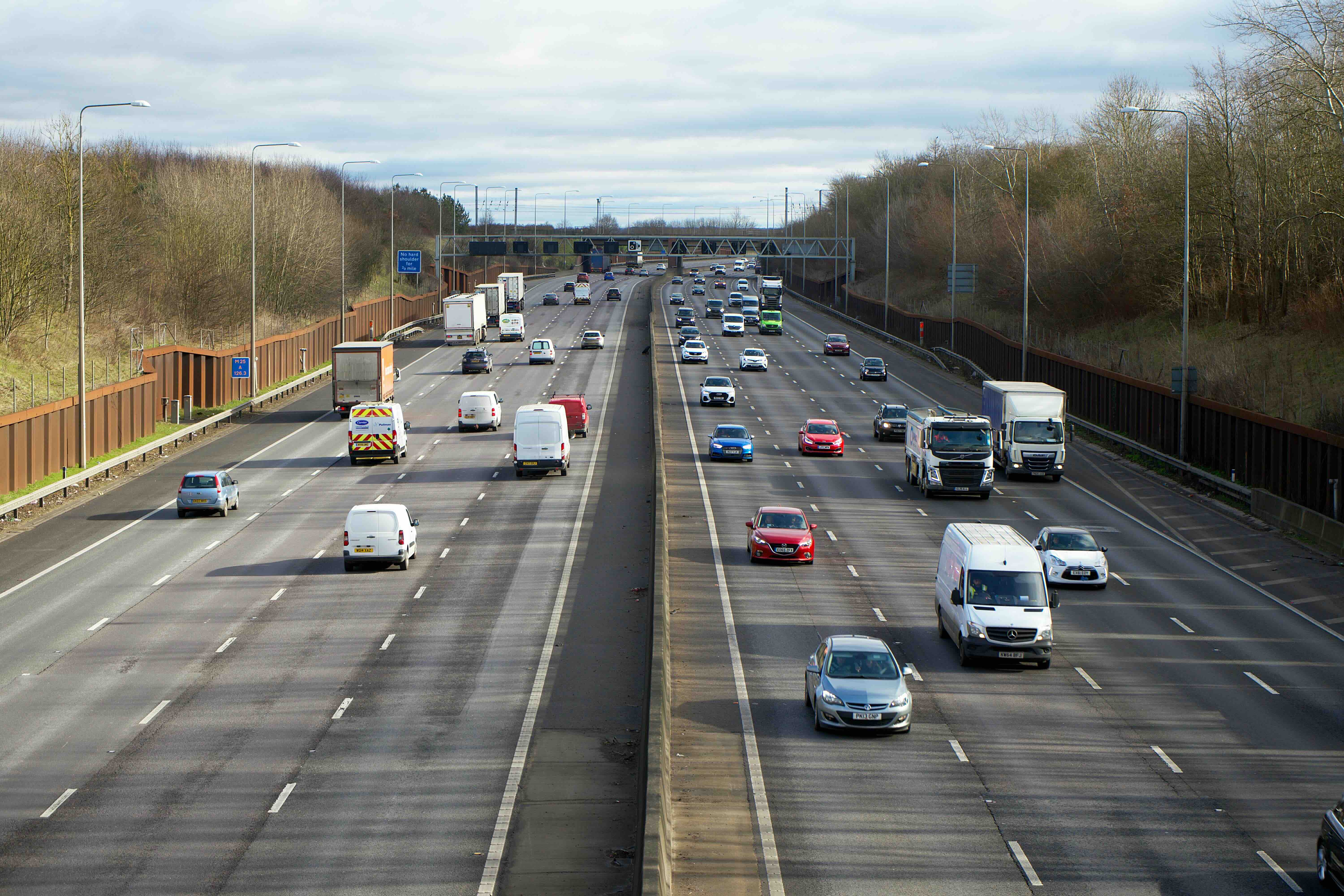 A generic image of a large motorway taken from a bridge. There are 8 lanes of traffic and vehicles travelling in both directions. 