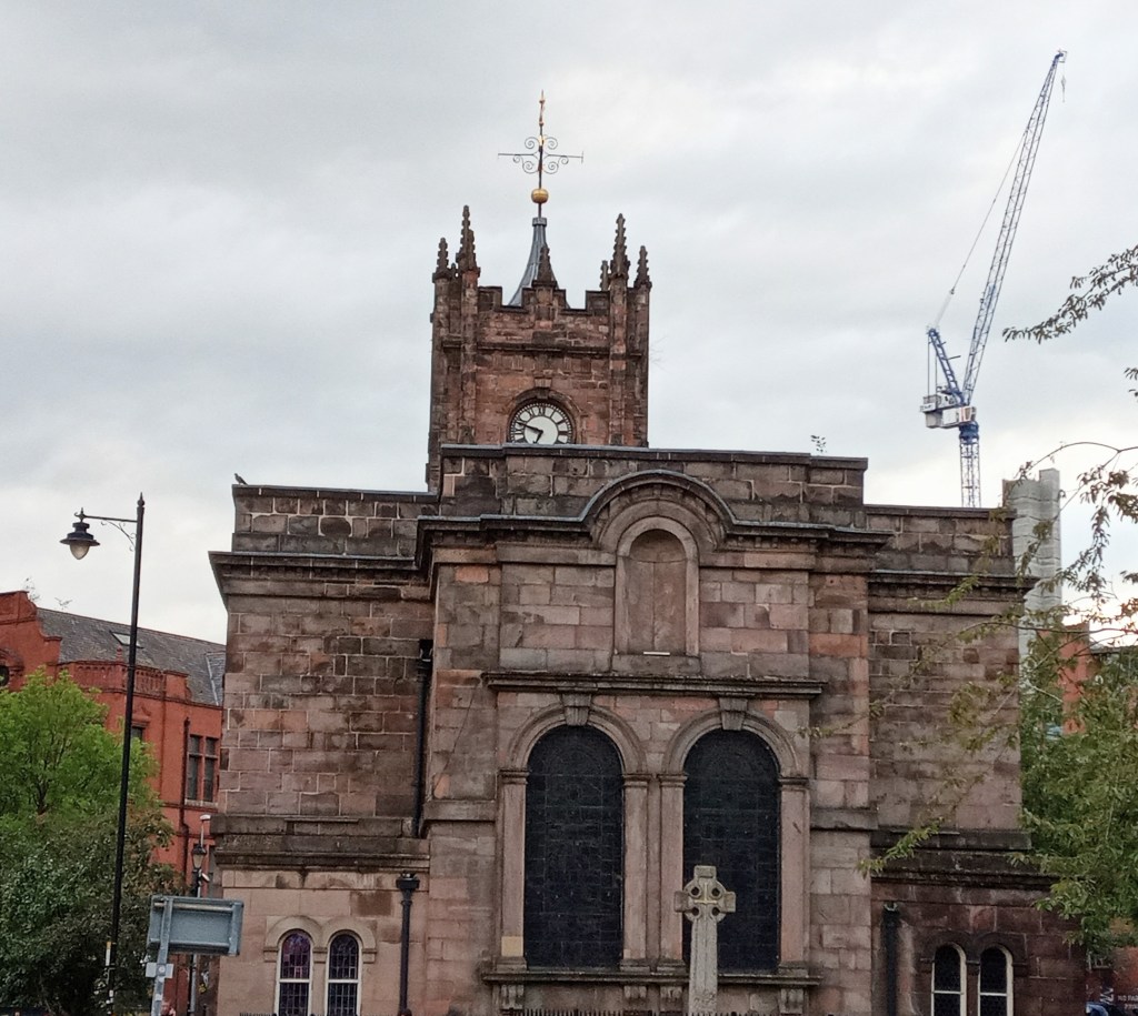 Sacred Trinity Church, Salford, from the east. It's a red sandstone building with a clocktower, originally founded in 1635.