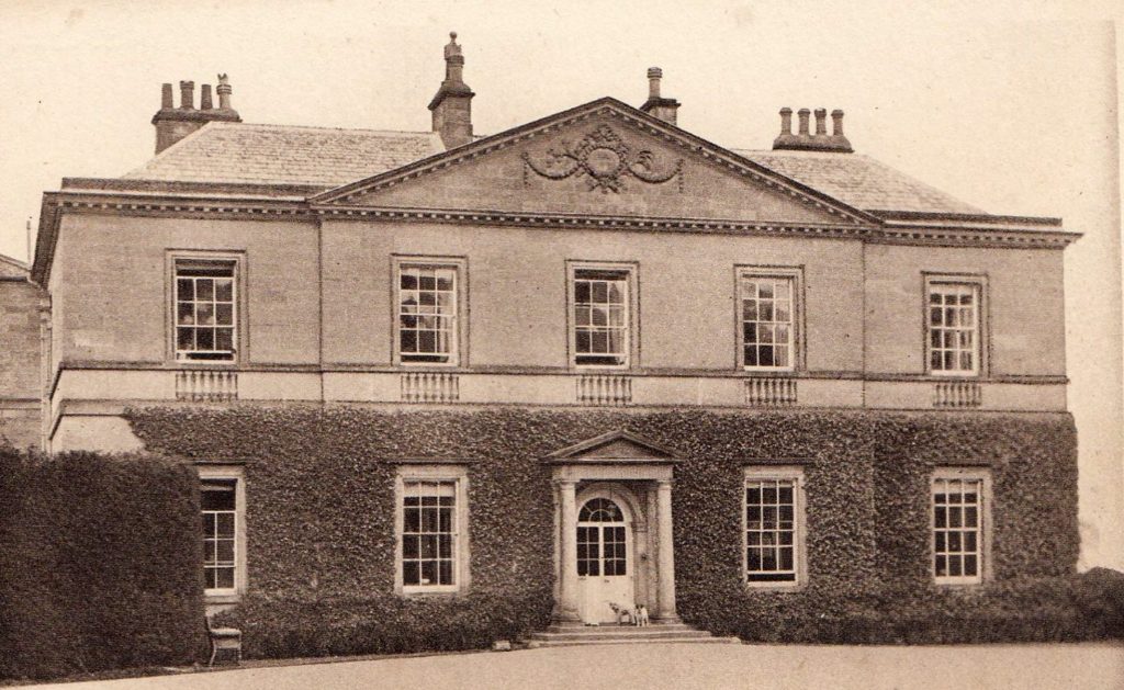 A sepia view of Middleton Lodge, a grand two-storey house with a pediment. There are five windows visible on the upper floor, and four either side of the front door on the lower floor, whose walls are covered in ivy. Two dogs are standing in front of the door. Postcard from about 1900, public domain, via Wikimedia Commons
